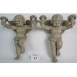 A pair of decorative old painted wooden wall mounted candle holders, modelled as cherubs,