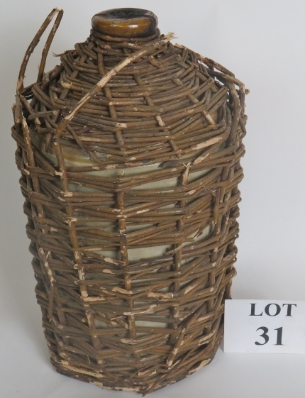 A vintage gallon of dark Navy rum in a stoneware jar, with wicker cover,