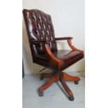 A 20th Century swivel desk chair upholstered in a deep burgundy leather,