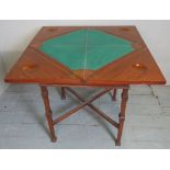 An Edwardian crossbanded envelope card table with a drawer to one side over lower stretcher,