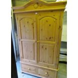 A 20th century pine double wardrobe with arched panelling to doors over 2 drawers to base,