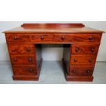 A Victorian mahogany writing desk with a carved gallery rail to back over 8 drawers with turned