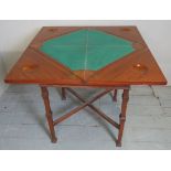 An Edwardian cross banded envelope card table with a drawer to one side over lower stretcher,