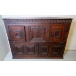 A 19th century solid oak cupboard with a central carved panel flanked either side by cupboards with