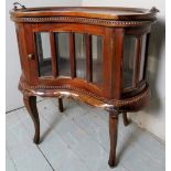 A c1900 style mahogany kidney shaped drinks cabinet with glass sections over detailed legs,