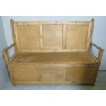 A late Victorian/Edwardian pine settle with a panelled back over a lift up storage compartment,