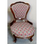 A 19th century mahogany nursing chair upholstered in a tapestry style material and terminating on