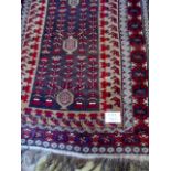 A 20th century Afghan rug on deep red gr