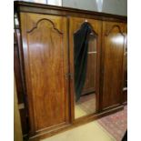 A 19th century oak and walnut triple wardrobe with a central mirrored door flanked either side by