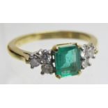 An 18ct gold ring set with centre emerald (8mm x 8mm) and six diamonds, size Q, boxed,