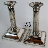 A pair of silver plate candlesticks in a corinthian column style, with square gadrooned bases,