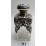 A silver scent bottle with silver hinged top and half covered silver embossed decoration,