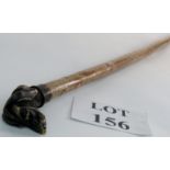 A long walking stick with cast brass dog's head handle, a natural bark shaft and brass ferrule,
