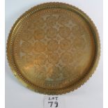 A large vintage Perisan hand beaten brass charger 53cm diameter on three feet,