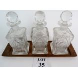 An Edwardian minimalist Tantalus with three matching decanters,