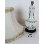 A ceramic table lamp decorated with floral patterns and birds on a wooden base, with shade,