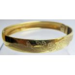 A 9ct gold flower engraved bangle, approx 10 grams,