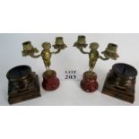 A pair of light brass candlesticks in the form of Satyrs supporting twin scones on red marble bases,