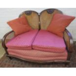 A 1920/30 2 seater Bergere sofa upholstered in pink with loose cushions,