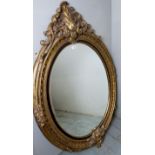 A large 20th century oval carved gilt framed wall mirror, 60" high,