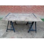 A vintage rustic trestle table made from an old door with iron strap hinges on two contemporary