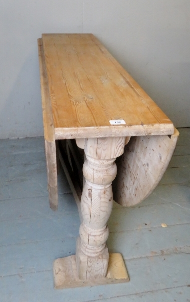 A large solid pine drop leaf oval dining table with turned bulbous end supports,