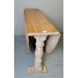 A large solid pine drop leaf oval dining table with turned bulbous end supports,