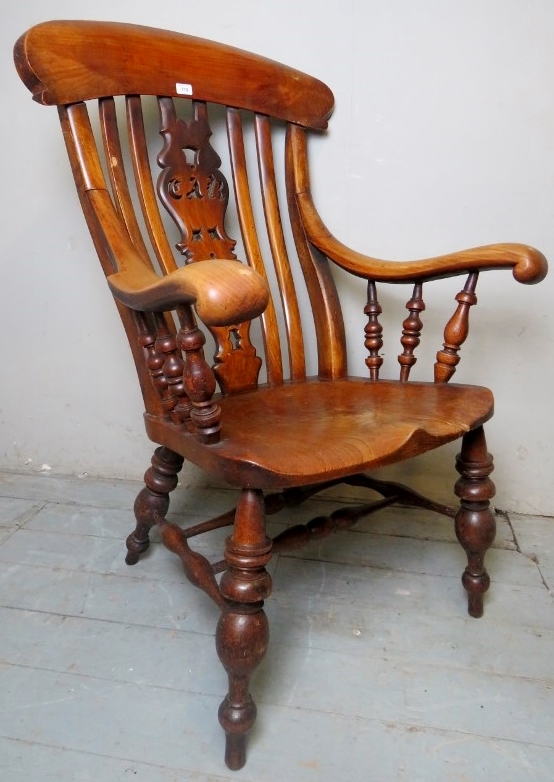 A large late 19th century/early 20th century Windsor fireside armchair with a carved back splat