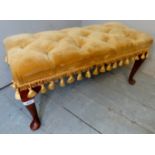 A small 20th century mahogany framed footstool, upholstered in gold buttoned material,