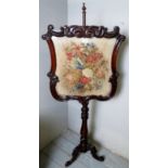 A fine Victorian mahogany carved pole screen with a needlework panel depicting flowers,