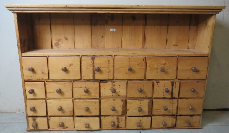 A fine Victorian pine wall mounted spice cabinet with a single shelf over 27 drawers,