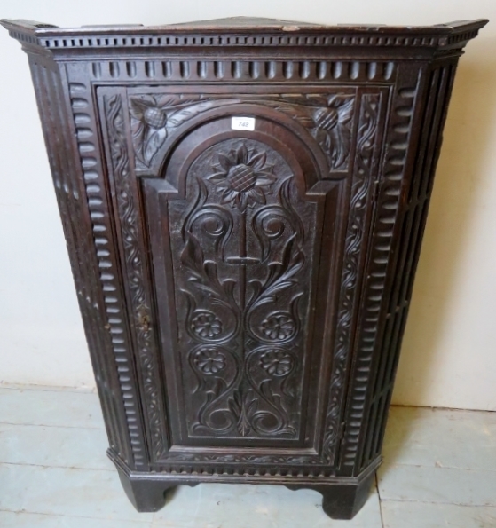 A Victorian carved oak corner cupboard with a carved panelled door over bracket feet,