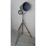 A vintage metal spotlight converted lamp, on an adjustable tripod base,