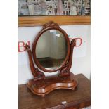 A VICTORIAN MAHOGANY OVAL PLAIN PLATE DRESSING TABLE MIRROR on twin carved fancy supports, on a