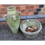 A WELL WEATHERED TERRACOTTA GARDEN URN together with a low circular CAST CONCRETE PLANTER