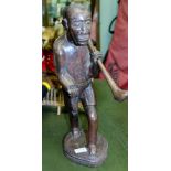 AN AFRICAN HARDWOOD FIGURAL CARVING OF A WALKING MAN, carrying a club over his shoulder, upon an