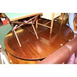 A REPRODUCTION MAHOGANY DINING TABLE OF OVAL FORM WITH CROSS BANDED EDGE SUPPORTED ON A FOUR POINT