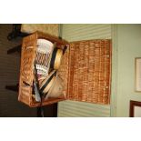 A WOVEN WICKER HAMPER containing a selection of hats, model vehicles and other interesting items