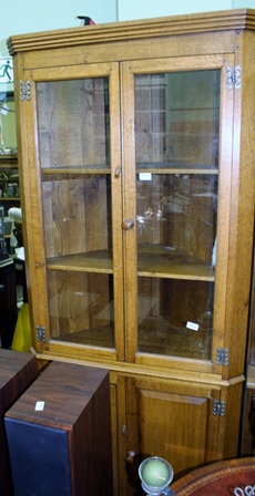 A MID 20TH CENTURY OAK FINISHED CORNER UNIT, with two plain glazed cupboard doors revealing