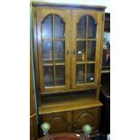 A LATE 20TH CENTURY OAK FINISHED BOOKCASE, the upper section having two arched panelled cupboard