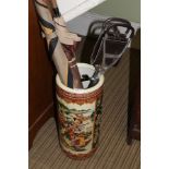 AN ORIENTAL DESIGN CYLINDRICAL POTTERY STICK STAND containing a shooting stick & brollies