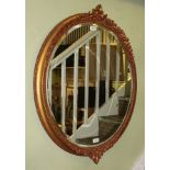 A LARGE OVAL BEVEL PLATE WALL MIRROR with fancy moulded gilt frame with grape & vine leaf decoration