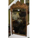 A GEORGIAN DESIGN FANCY GILT FRAMED PLAIN PLATE WALL MIRROR with elaborate crest