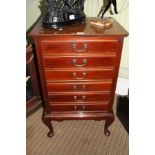 AN EARLY 20TH CENTURY MAHOGANY FINISHED MUSIC CABINET of six fall down front drawers supported on