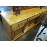 A DISTRESSED PINE FINISHED LOW DRESSER having rectangular top with three inline drawers over four