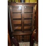 A LATE 20TH CENTURY OAK FINISHED BOOKCASE UNIT WITH TWIN GLAZED UPPER DOORS WITH SHELVED INTERIOR on