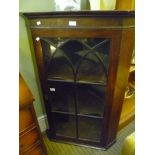 A 19TH CENTURY HANGING CORNER CUPBOARD with arched design bar glazed door, opening to reveal shelved