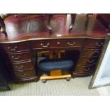 A FANCY SHAPED ONE PIECE MAHOGANY FINISHED KNEE HOLE DESK with skiver insert top, having central