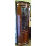 A MODERN MAHOGANY COLOURED CORNER FREE-STANDING CUPBOARD with glazed upper door and panelled lower