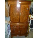 A REPRODUCTION BEVAN FUNNELL WALNUT COLOURED BOW FRONT CABINET, the upper section having two doors